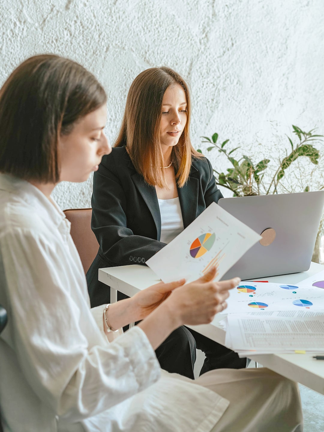 Fotografía que muestra a dos mujeres revisando gráficas de datos.